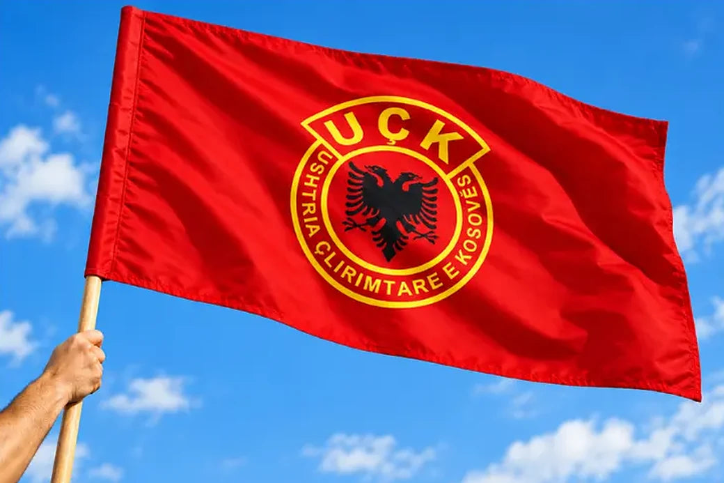 Drapeau UÇK Standard flottant sur une hampe en bois devant un ciel bleu